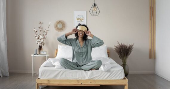 woman with eye mask sitting in bed smiling
